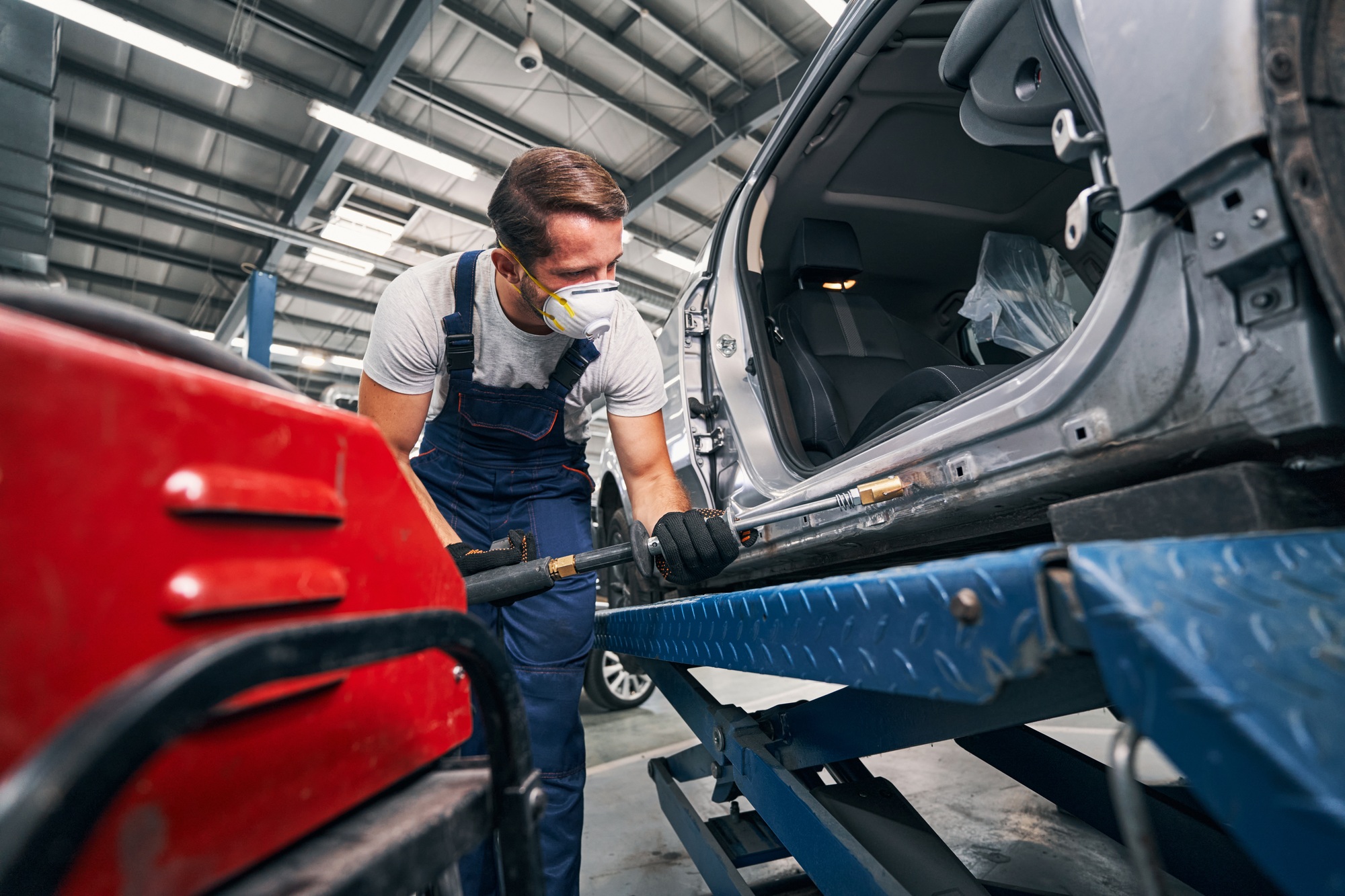 Repairman peening car with tool for removing dents